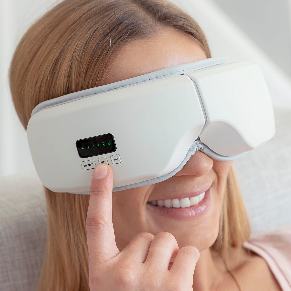 Personne souriante utilisant son appareil de massage oculaire